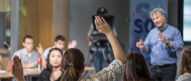 School of Communication at American University (student raising her hand in class)