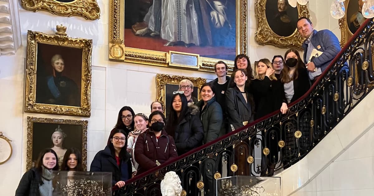 Tour group on the Hillwood's Grand Staircase with Russian royal portraits behind them.