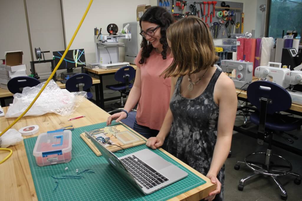 Two students work with a laptop, a small computer and a circuit board.