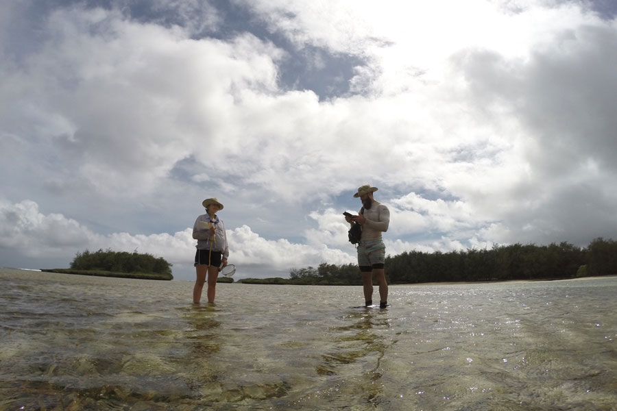 Two researchers in outdoor clothing stand in a lake