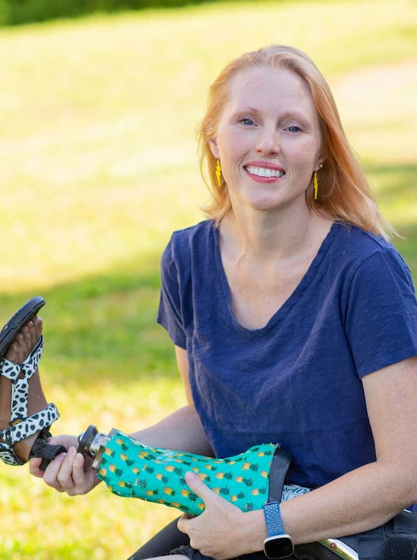 Dr. Ashley Shew in a sunlit field holding a prosthesis.