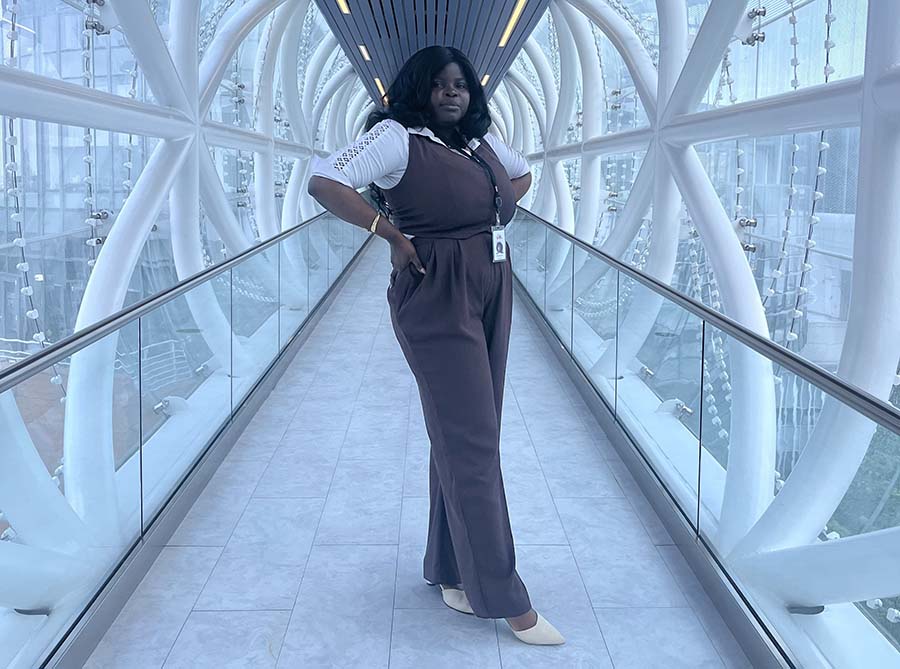 Oreoluwa Erinfolami on an elevated glass and metal catwalk in a modern building