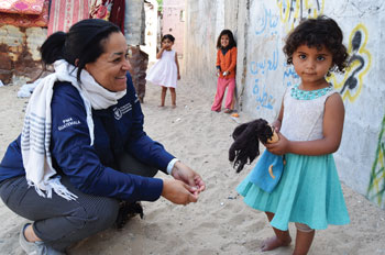 Valerie Guarnieri kneels next to a child