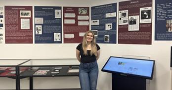 Ava Barabasz in front of an exhibit she created at Bender Library. Photo by Sydney Henry.