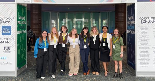 A group of AU students smile for a photo in front of the NCUR sign