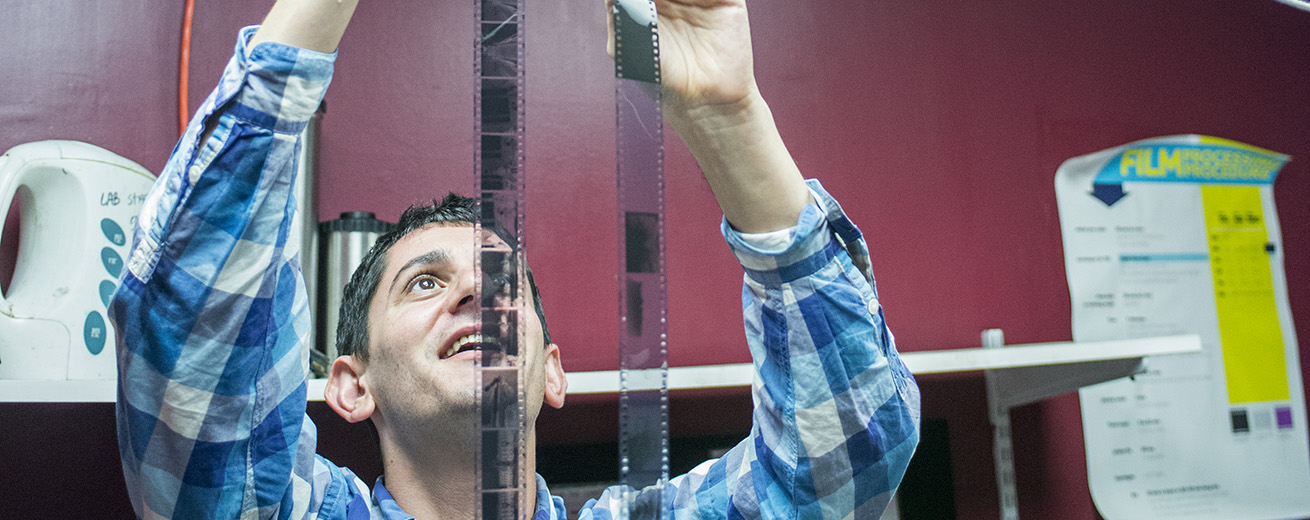 A student in our dark room holds film up to the light.