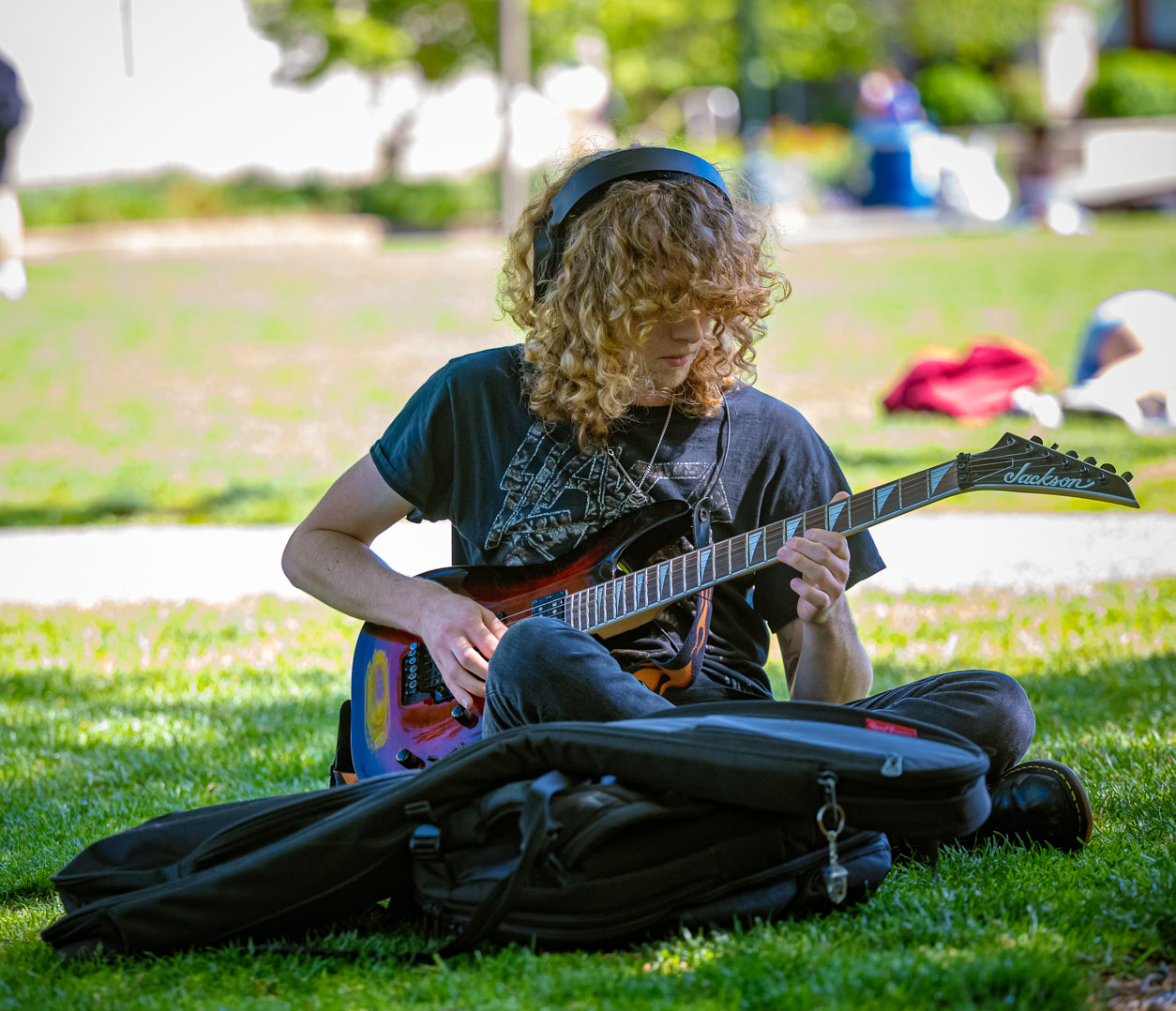 A student practices guitar on the quad