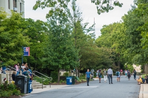 On campus with people walking, trees, and an AU flag.