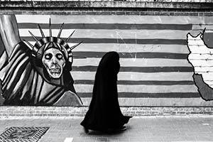 A woman walks in front of a mural in Tehran.