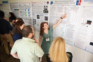 Female student presents poster to onlookers