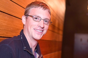 Washington Semester Program alum Ben Thomas poses in front of a wooden wall.