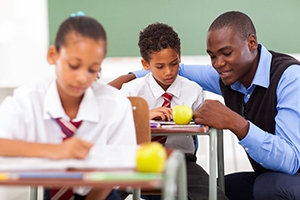 Elementary school teacher helping student in classroom